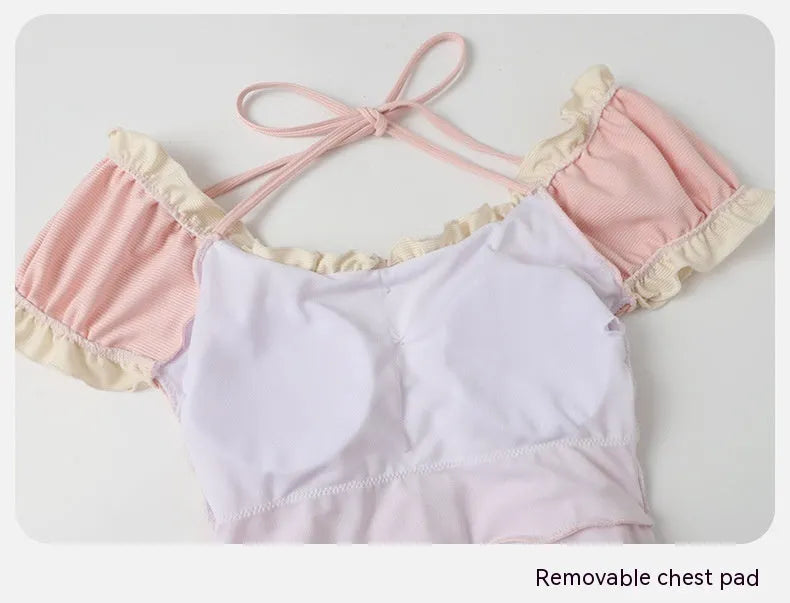 Pink women's conservative one-piece swimsuit with a Siamese design detail on a mannequin.