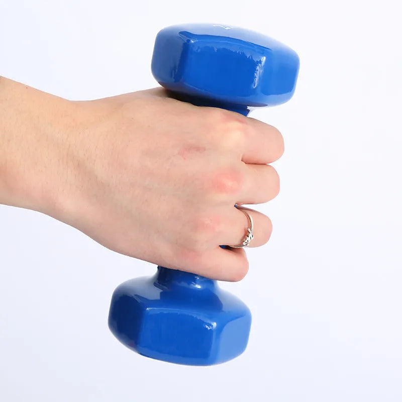 Set of bright coloured plastic fitness dumbbells in different weights on a floor.