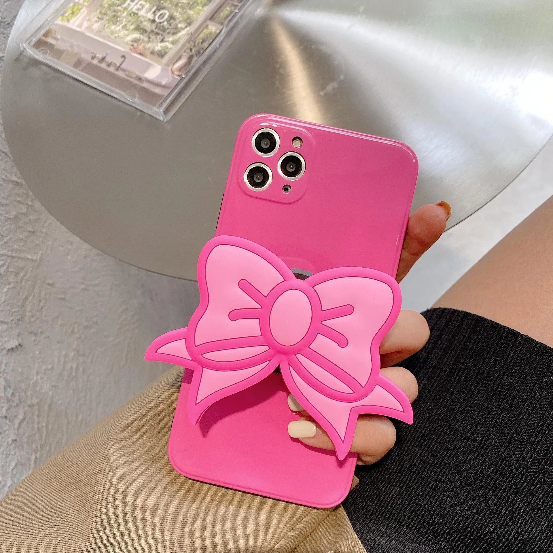 Rose red iPhone case with a large pink bow and a folded-out kickstand on the back.