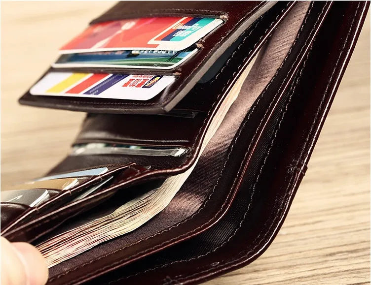 Men's black full-grain leather bifold wallet open, showing card slots, zip coin pocket, and banknote section.