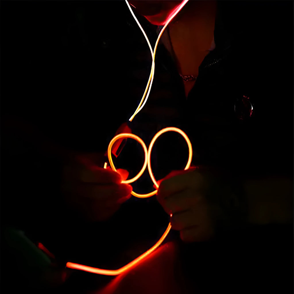 Blue, green, and pink LED earphones with glowing cables next to a smartphone, showcasing their music-reactive light feature.