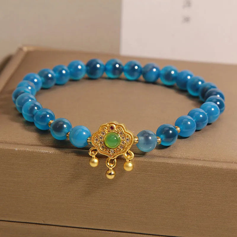 Blue sugar heart agate safety lock pendant on women's bracelet with alloy inlay and crystal accents.