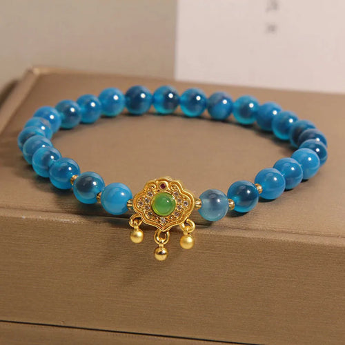 Blue sugar heart agate safety lock pendant on women's bracelet with alloy inlay and crystal accents.