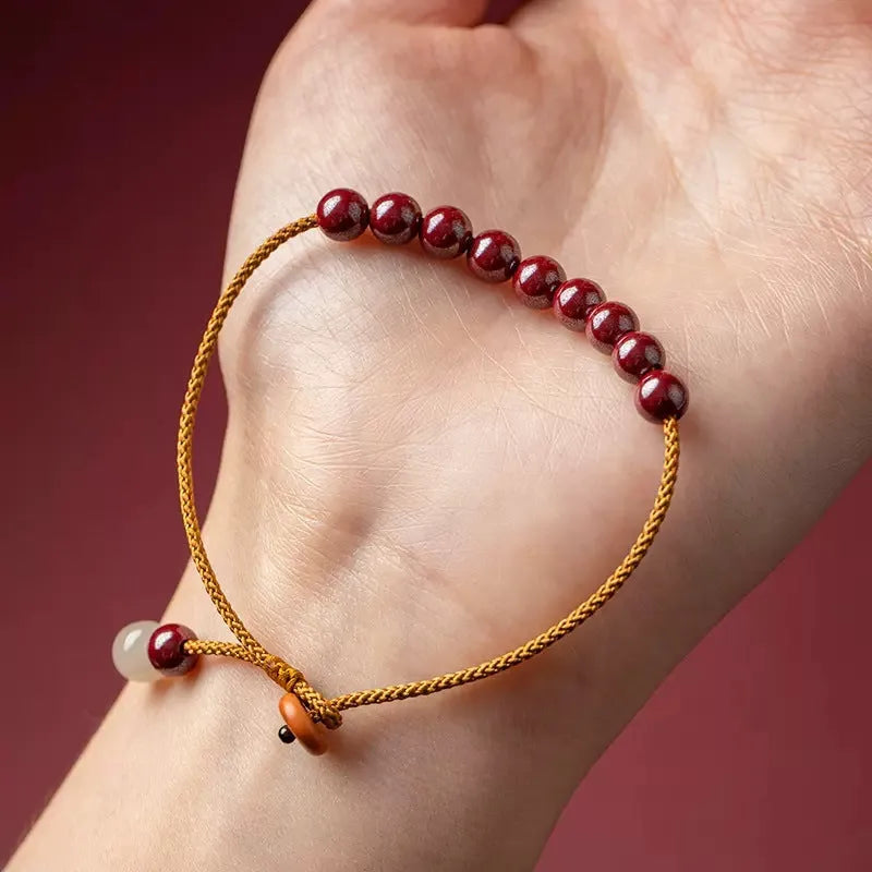 Hand-woven cinnabar and Hetian jade geometric bracelet on wrist showing natural stone textures