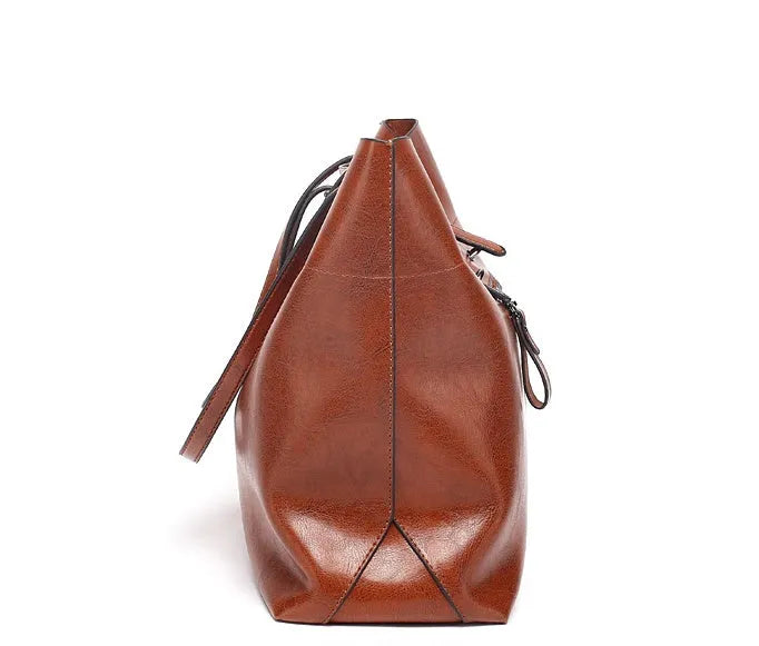 Brown waxed cowhide cross-body handbag showing front flap and adjustable shoulder strap.