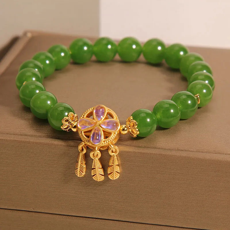 Green Jasper crystal bracelet with a four-leaf clover dream catcher pendant on a woman's wrist.