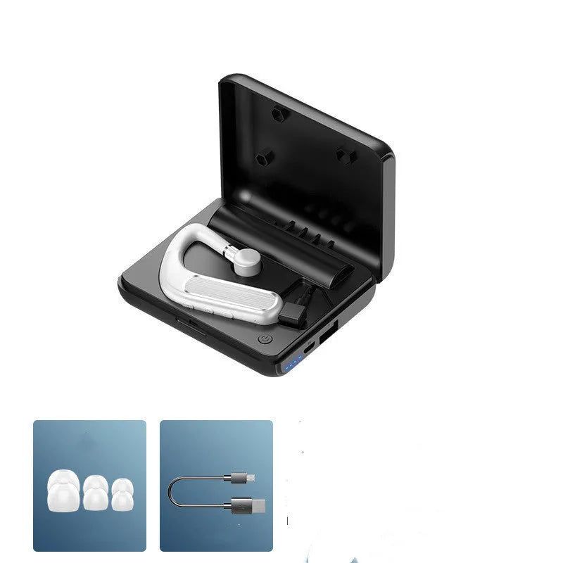 Black Bluetooth earphones with a charging warehouse case and silicone ear caps on a table.