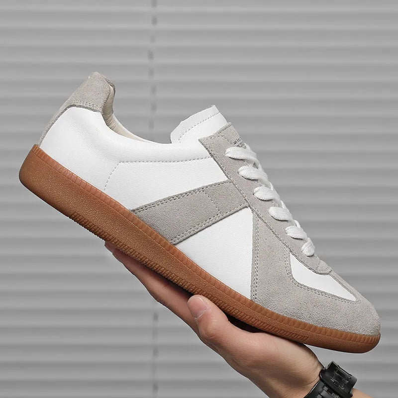 White low-top retro sneakers with round toe and lace-up front on a flat rubber sole.