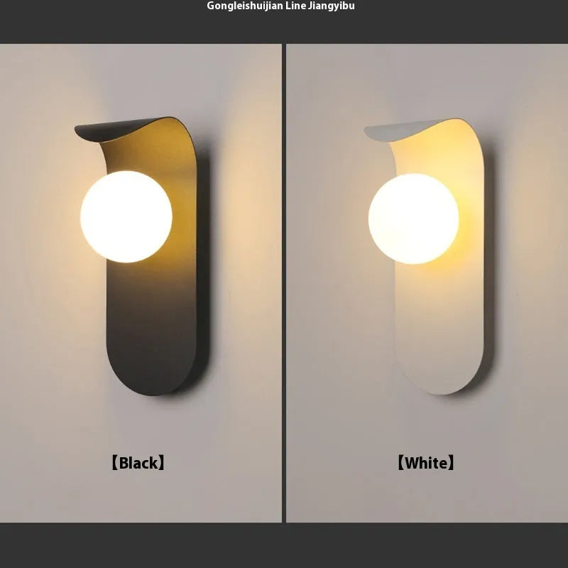 Modern minimalist wall lamp in black finish with LED warm light on a bedroom wall beside bed