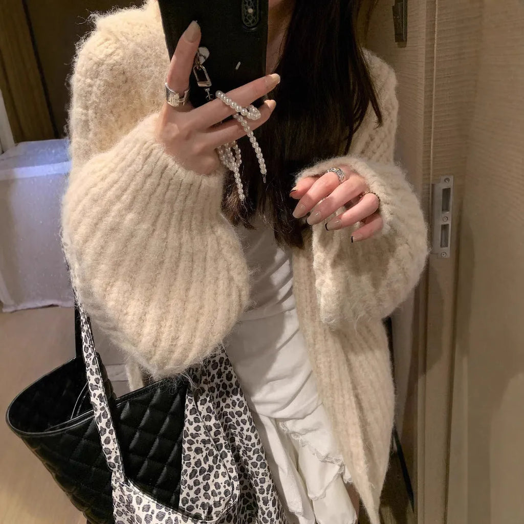 Woman wearing a brown retro-style chunky knit hooded cardigan with a loose fit.