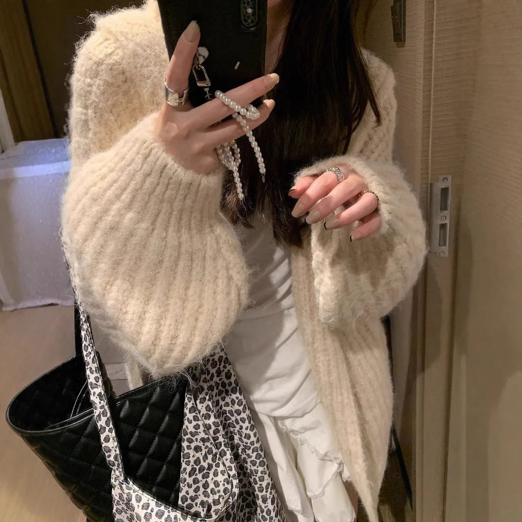 Woman wearing a brown retro-style chunky knit hooded cardigan with a loose fit.