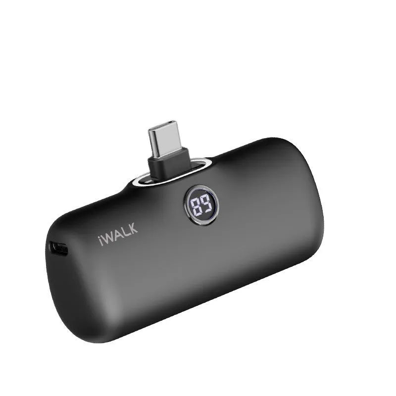Compact white lipstick-shaped power bank with digital battery percentage display on a wooden table.