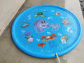 Blue children's water spray play mat with marine animal graphics on grass connected to a hose