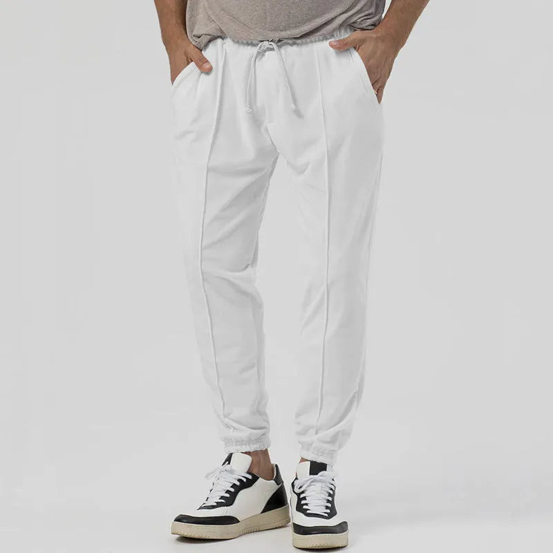 Man wearing grey loose tapered track sweatpants with a micro-elastic cotton blend fabric.