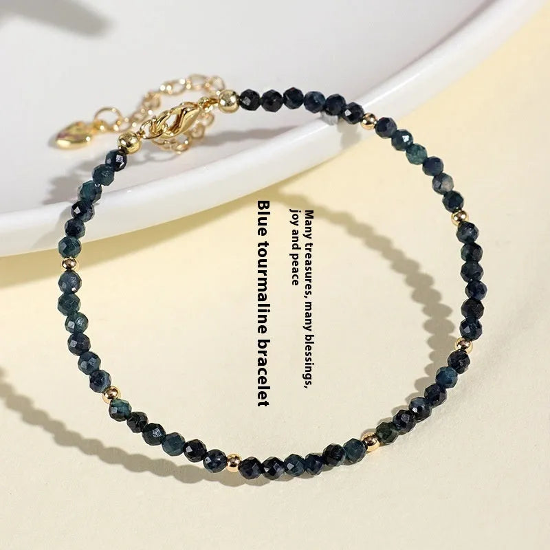 Blue tourmaline gemstone bracelet with 3mm cut beads on a white background.
