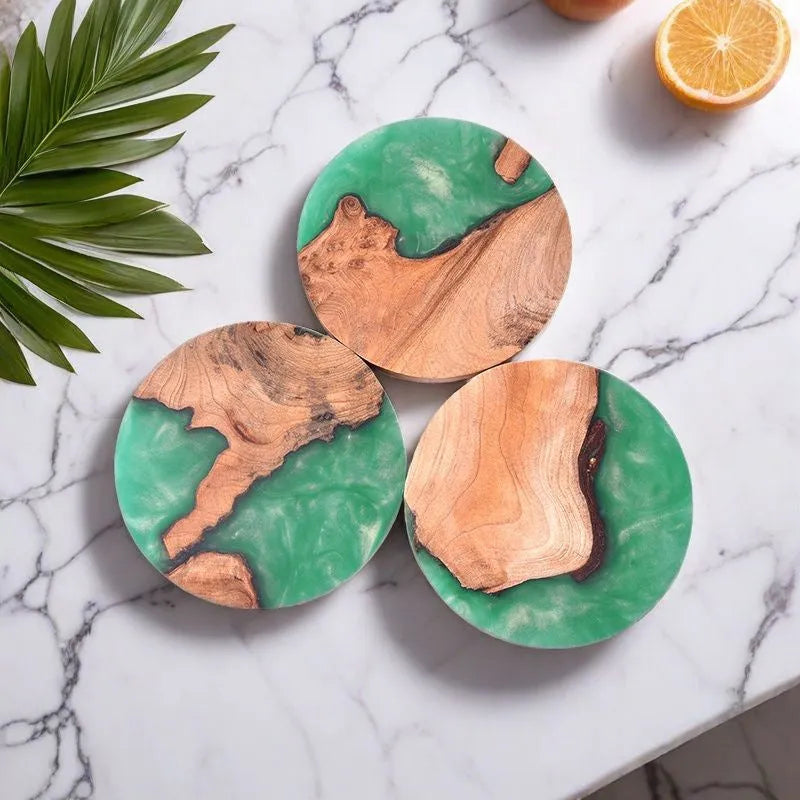 Set of four solid-colour wooden coasters in irregular round and square shapes on a wooden table.