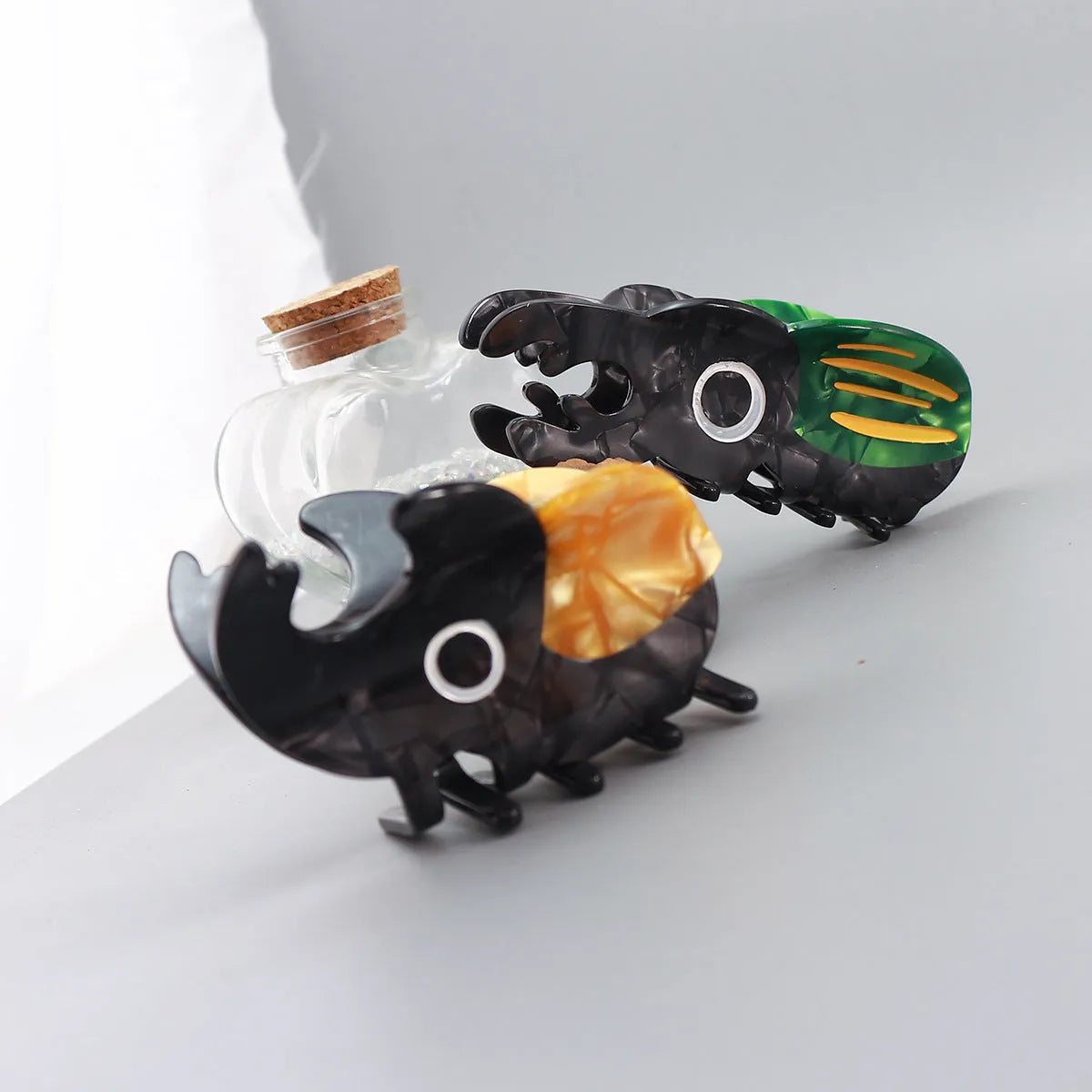 Handmade green beetle grip clip made from cellulose acetate on a desk with papers.