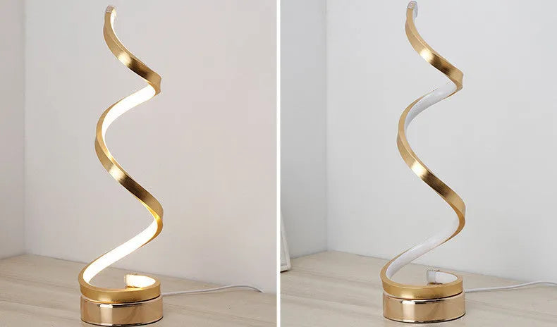 Modern LED table lamp with gold metal base and curved acrylic shade on a desk