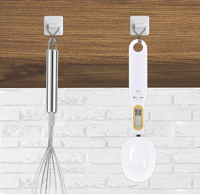 Black electronic digital scale with integrated measuring spoon showing weight display.