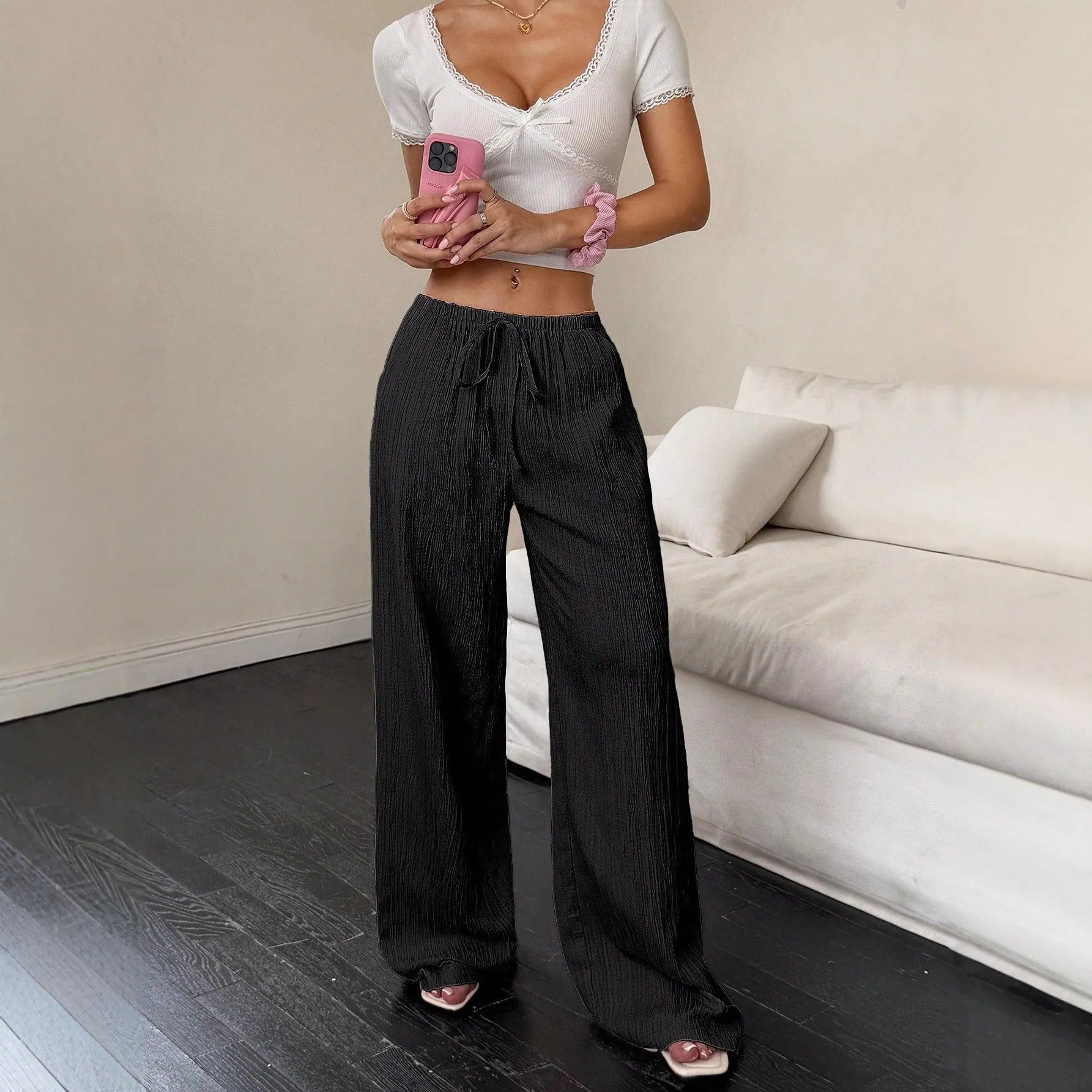 Women's black wide-leg trousers with a front lace-up waist detail on a neutral background.