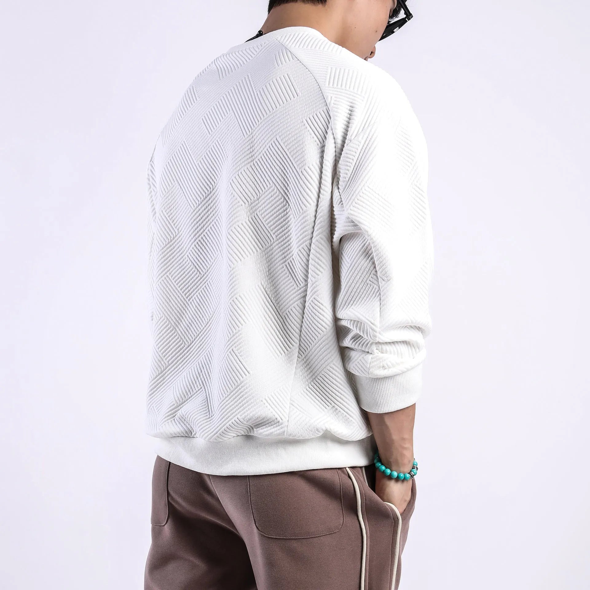 Men's loose fit solid colour twill jacquard pullover sweater on a hanger.