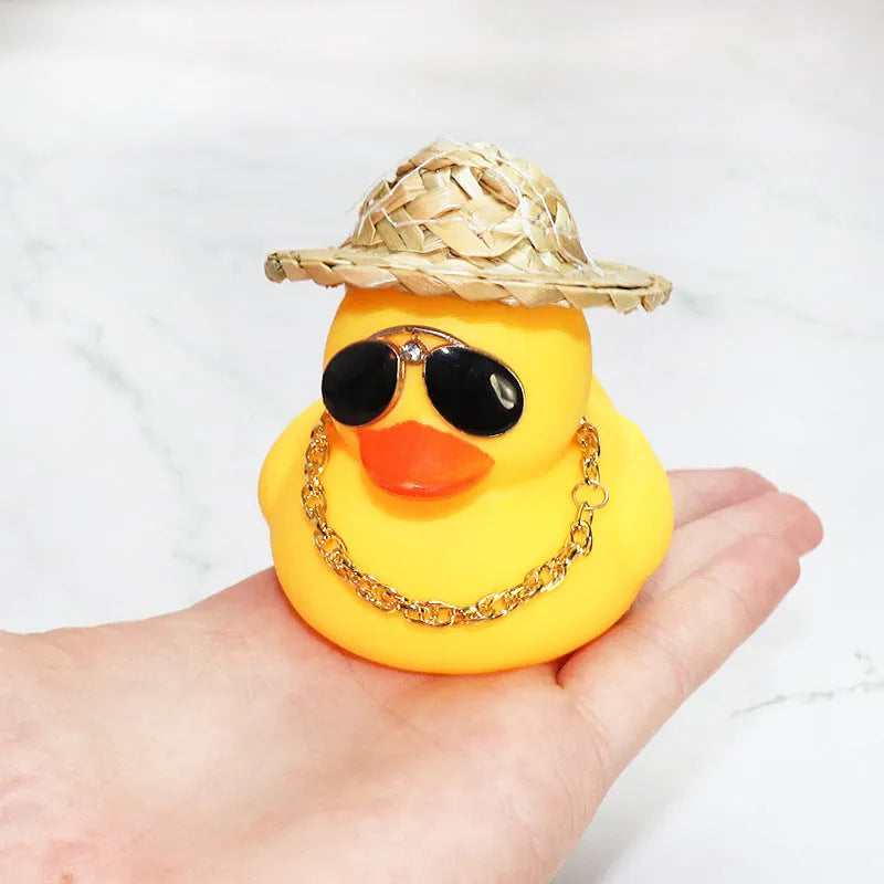 Straw hat yellow duck car ornament with adhesive gel and miniature sunglasses accessory on car dashboard
