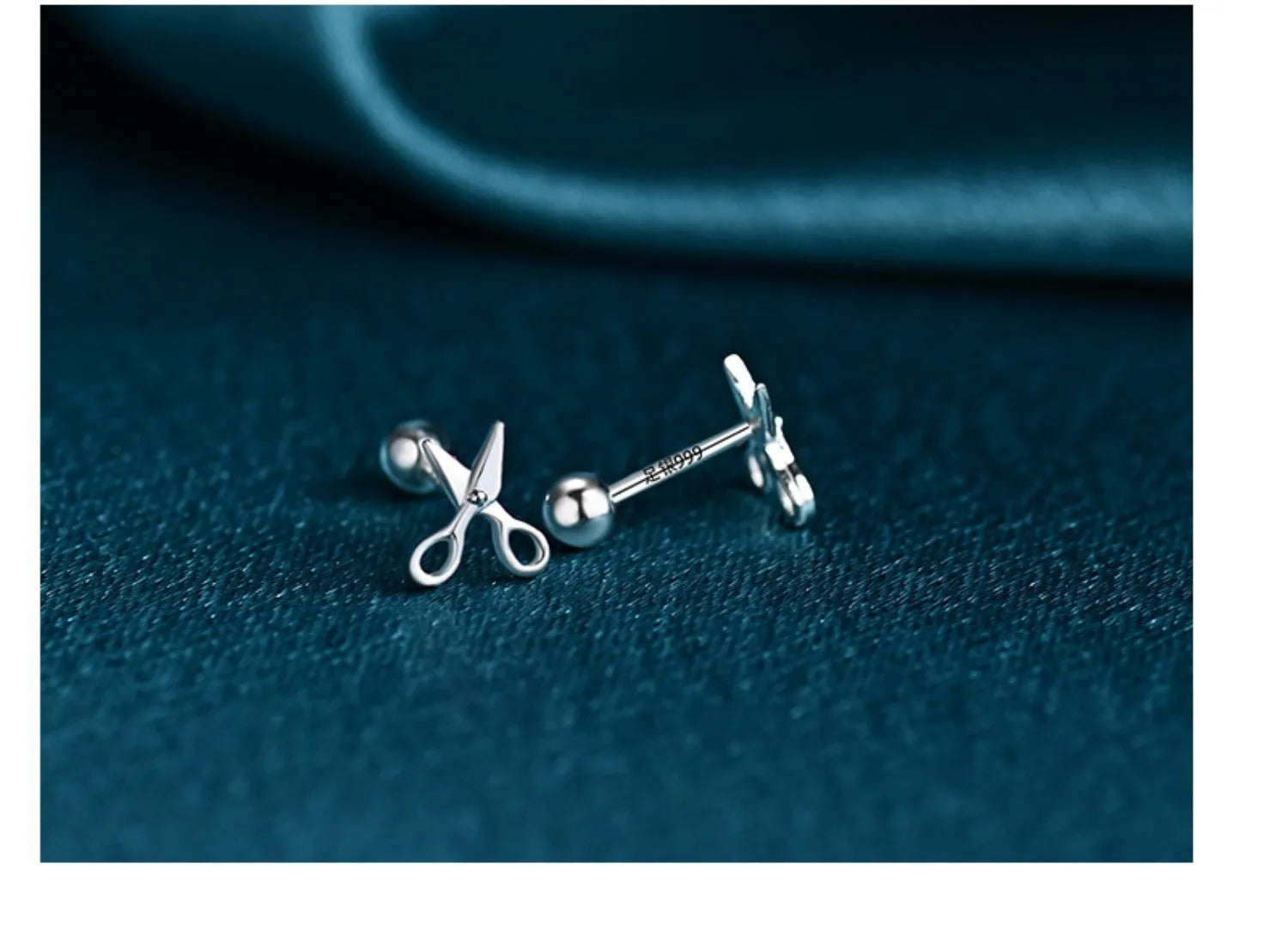 A pair of screw-back earrings made from 999 pure silver with a miniature silver scissors charm.