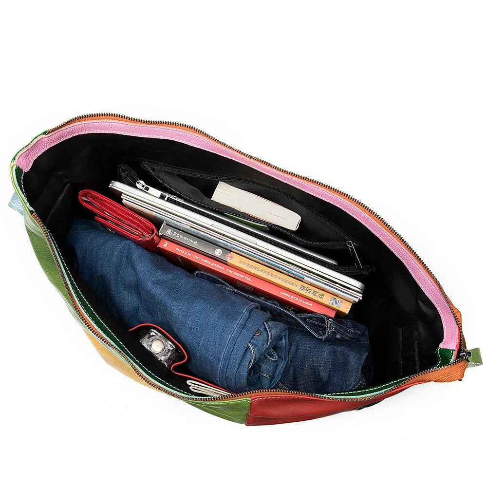 Brown cowhide leather crossbody travel bag with stitching detail, shown with laptop and A4 magazine.