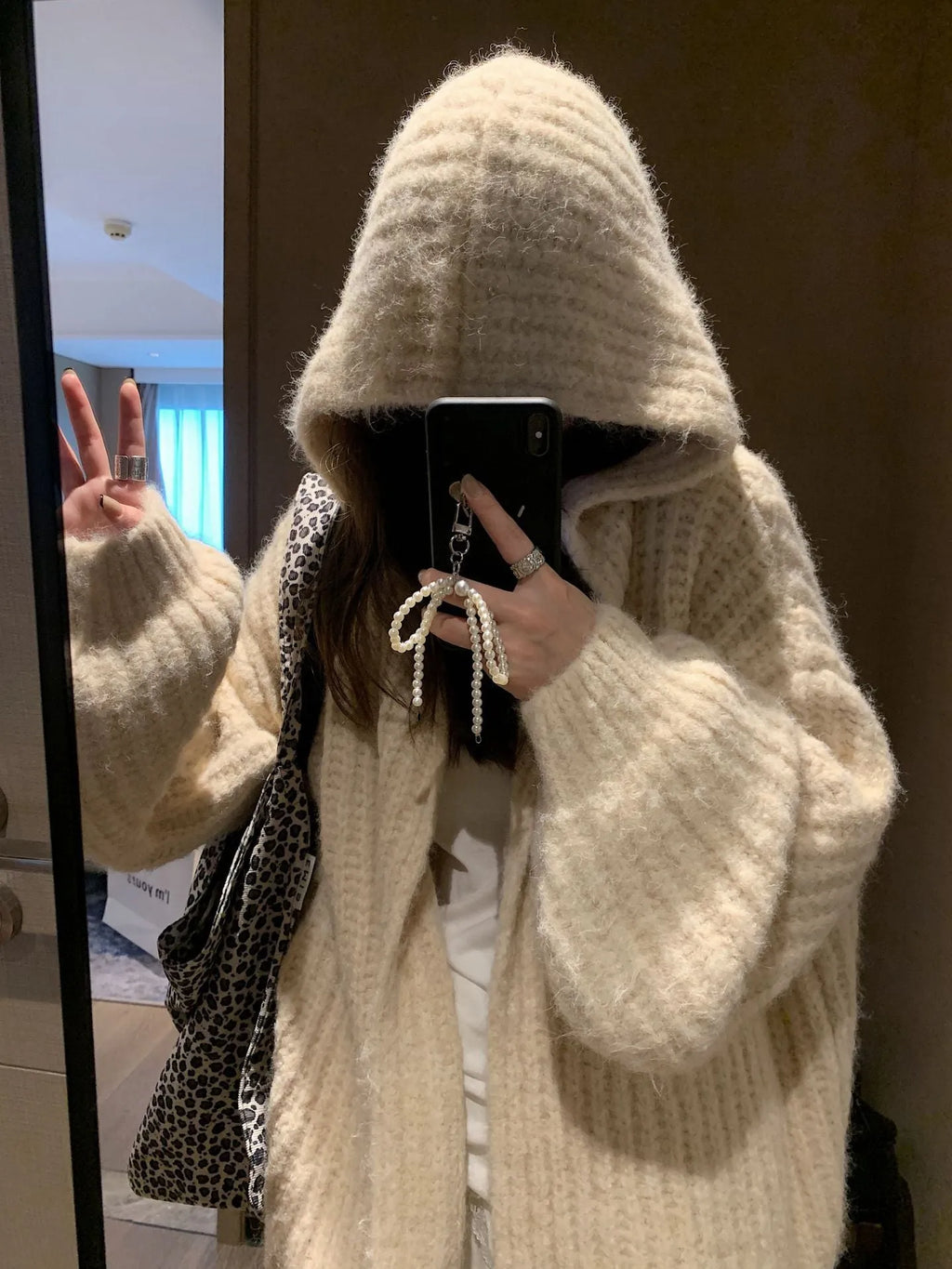 Woman wearing a brown retro-style chunky knit hooded cardigan with a loose fit.