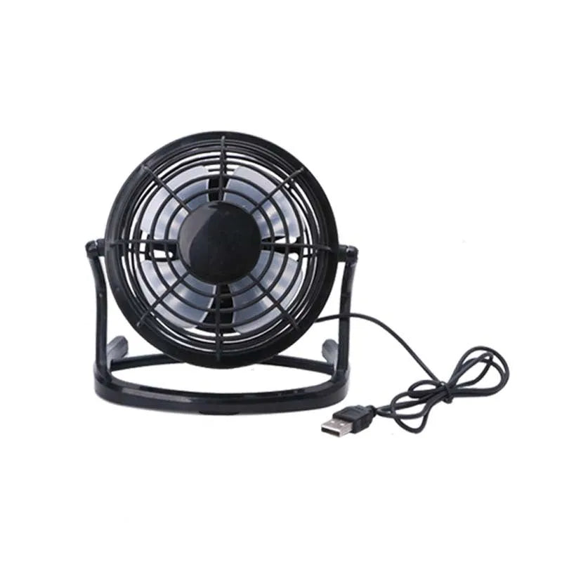 Small black and white USB desk fan with adjustable angle on a wooden table.