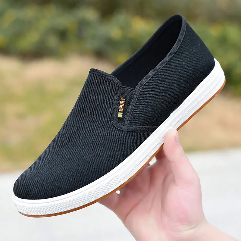 Men's low-top black canvas slip-on shoes with round toe and shallow mouth on a composite sole.
