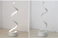 Modern LED table lamp with gold metal base and curved acrylic shade on a desk