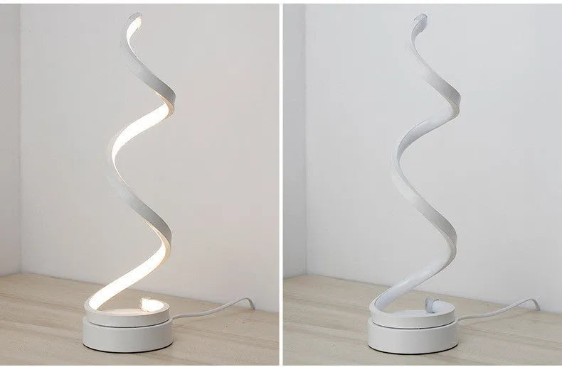Modern LED table lamp with gold metal base and curved acrylic shade on a desk