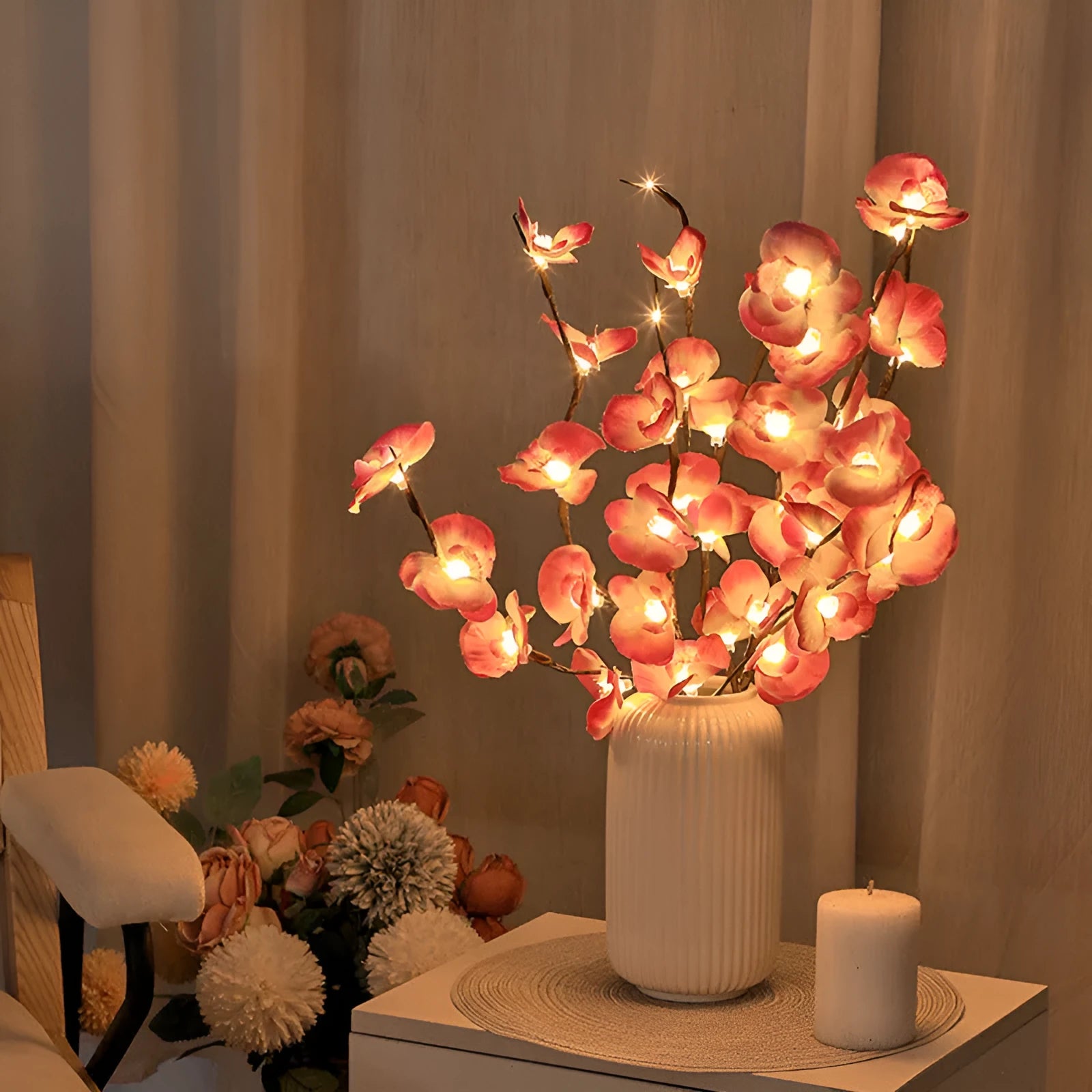 Pink fabric and plastic LED Phalaenopsis orchid branch light, 65cm long, on a table providing warm white ambient glow.
