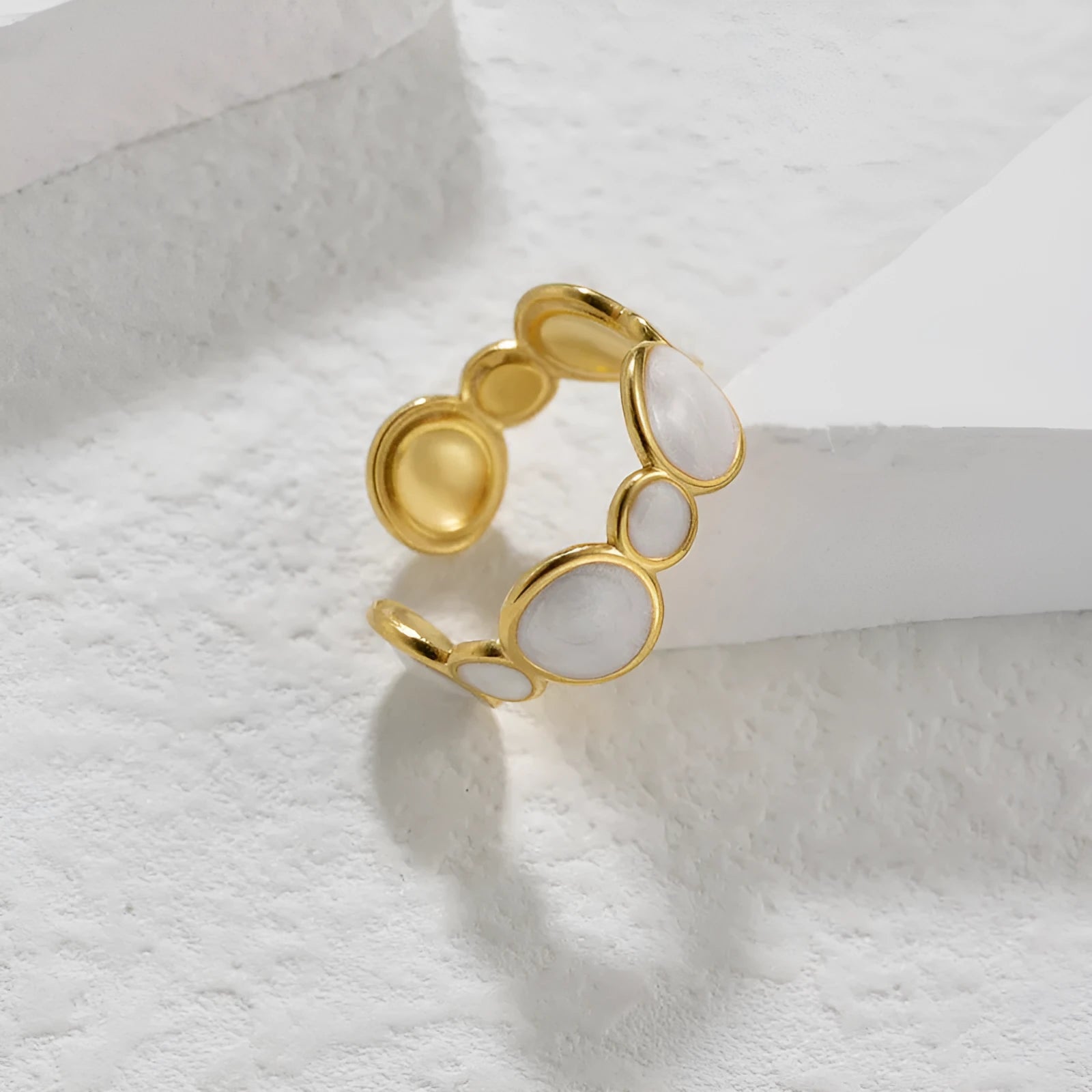 A stainless steel ring with a geometric design and adjustable opening on a plain background