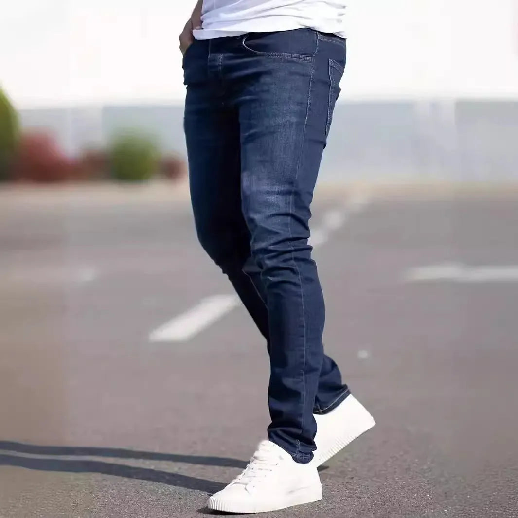 Dark blue men's slim-fit cotton jeans with a skinny leg opening on a plain background.