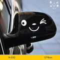 Pair of reflective cartoon car stickers with cute eyes on a car rearview mirror.