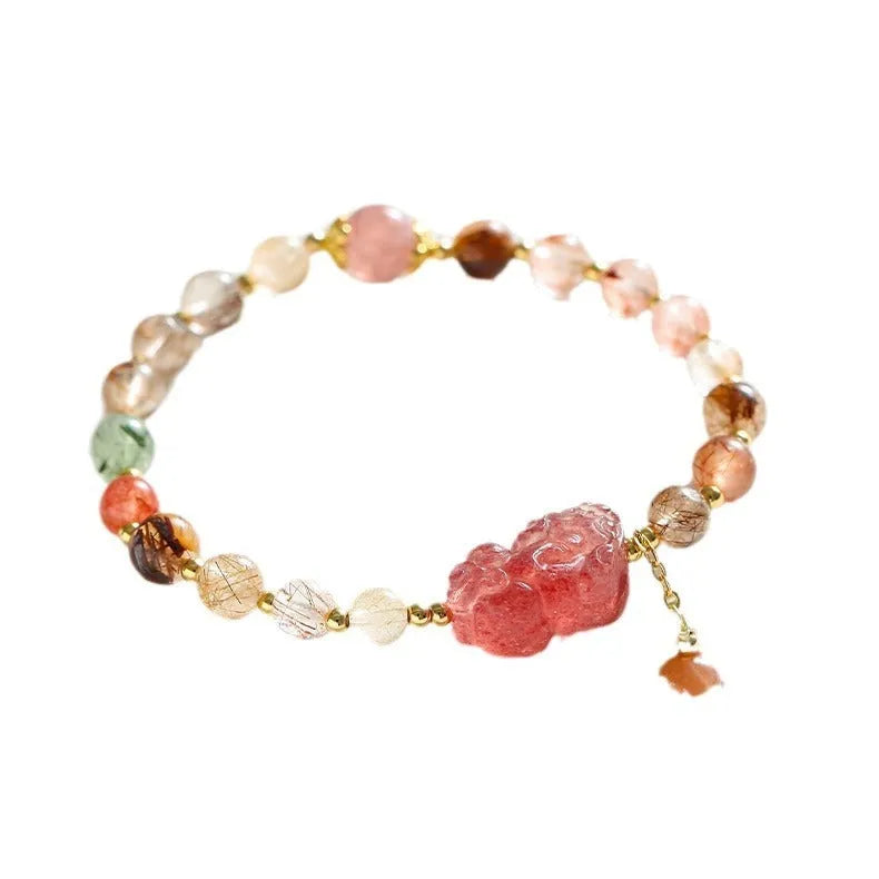 Close-up of a women's copper bracelet with a pink Strawberry Quartz crystal, a detailed Pixiu charm, and a white freshwater pearl.
