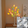 White plastic birch tree Easter decoration with warm white LED lights and hanging coloured eggs on adjustable branches.