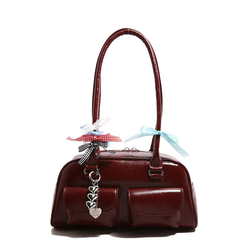 Retro-style brown PU leather women's pillow handbag with a one-shoulder strap, shown with a decorative ribbon pendant.