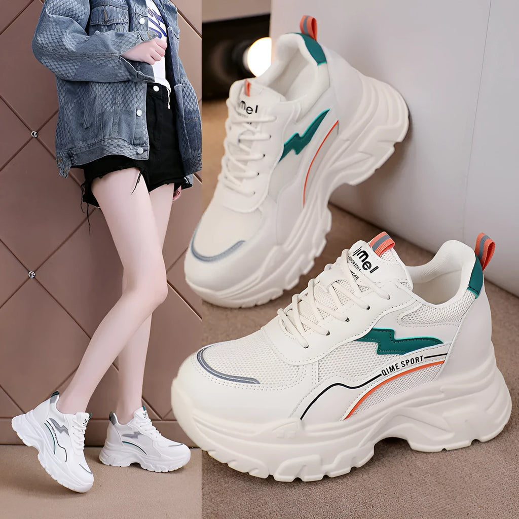 Women's white low-top sports trainers with cross shoulder straps and a lace-up front on a solid background.