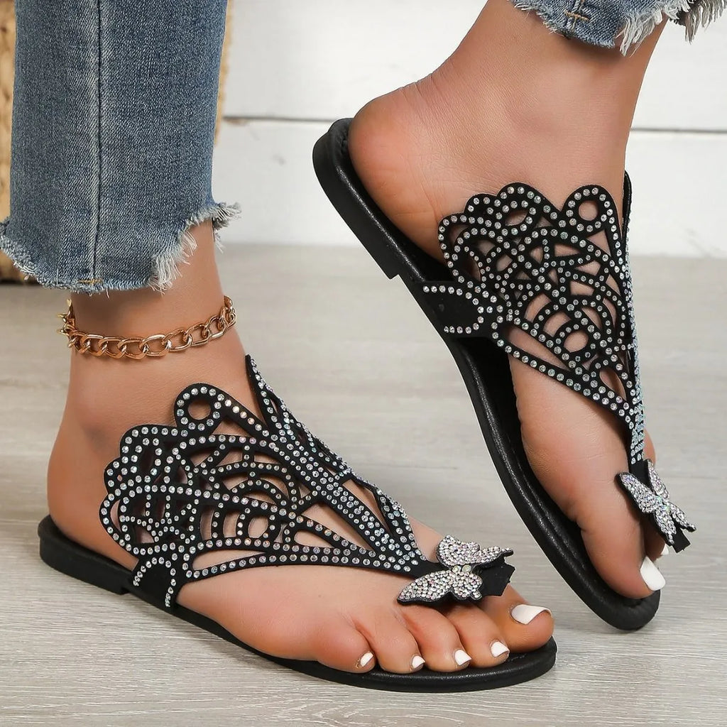 Women's black slip-on sandals with rhinestone decoration and an open flip-toe design on a flat rubber sole.