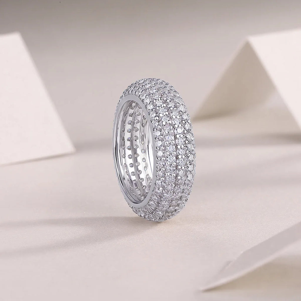 Moissanite wedding ring with S925 silver platinum plated band on flat surface showing stone and certificate