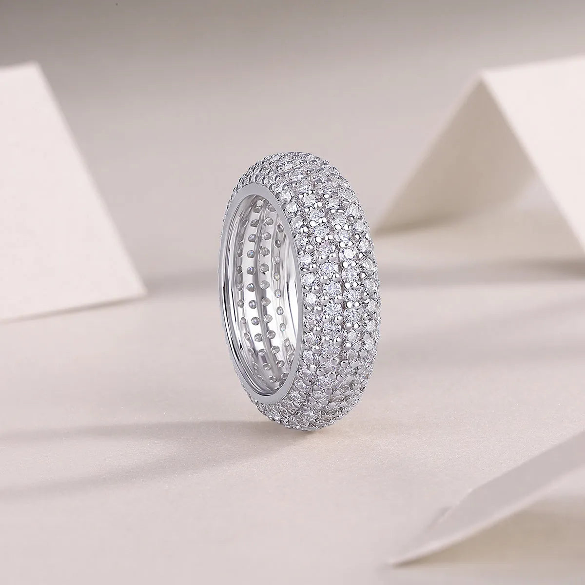 Moissanite wedding ring with S925 silver platinum plated band on flat surface showing stone and certificate
