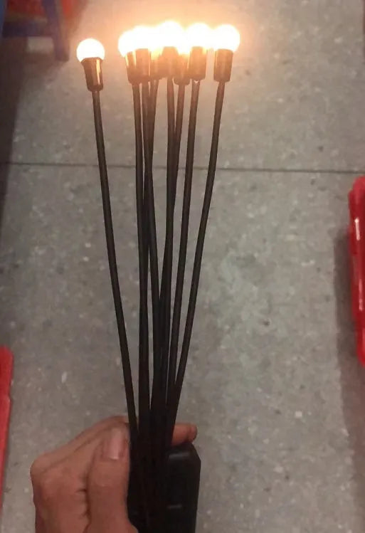 Solar-powered LED firefly garden spike light with multiple heads and a press-in ground plug on grass.