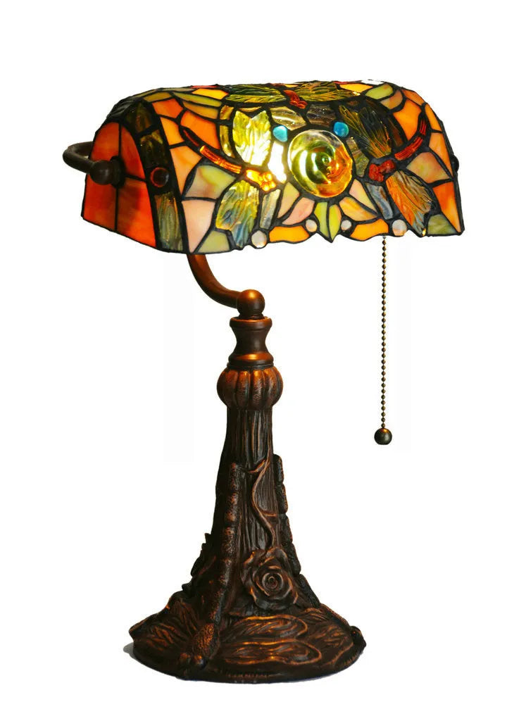 Colourful Tiffany-style stained glass table lamp with resin base on a wooden desk.