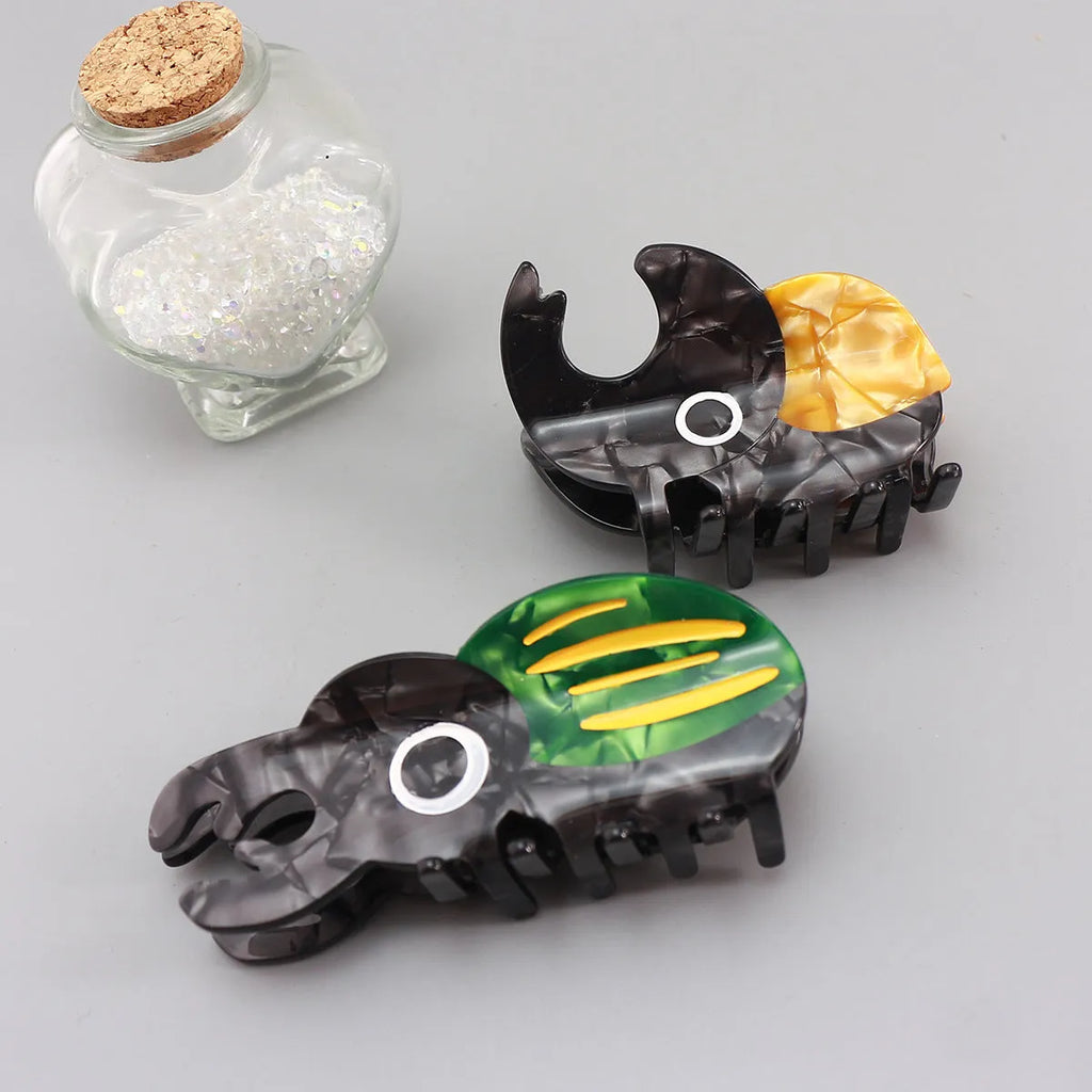 Handmade green beetle grip clip made from cellulose acetate on a desk with papers.