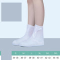 White high-top reusable PVC waterproof shoe covers with anti-skid sole on a wet surface.