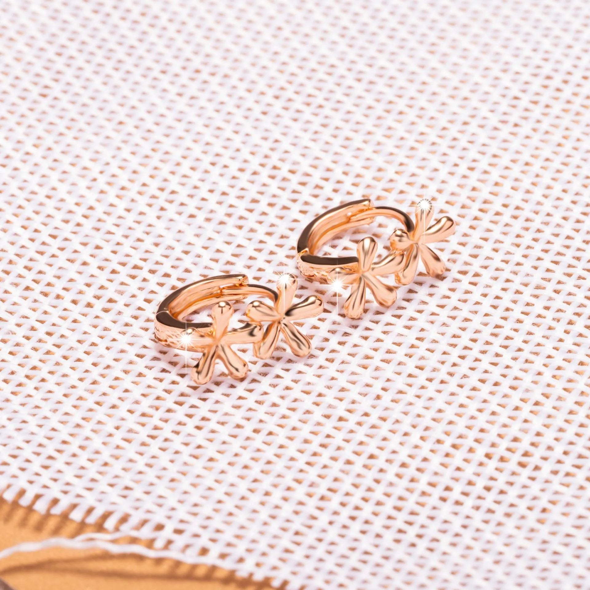 Circular rose gold earrings with a waterdrop flower pattern, shown front-on.