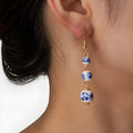 Long blue and white porcelain ceramic bead earrings with geometric alloy details on a white background.